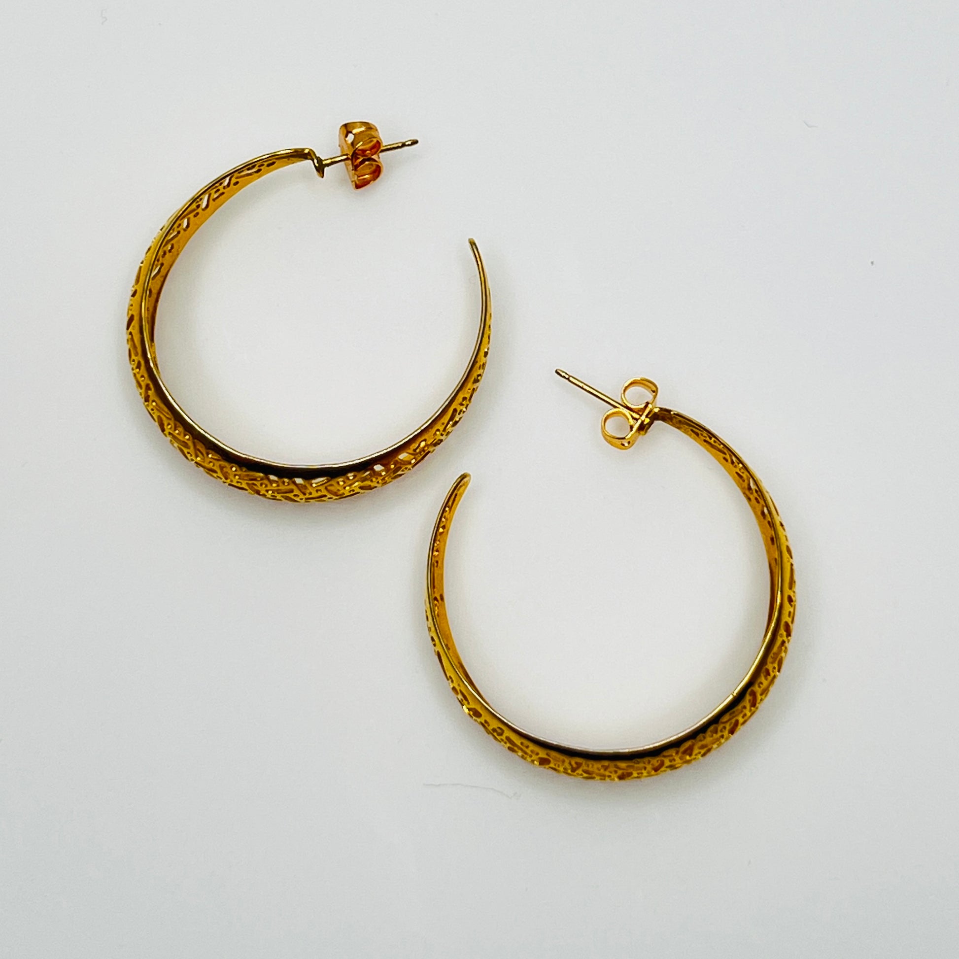 Domed gold-tone hoops with intricate lattice design, side view