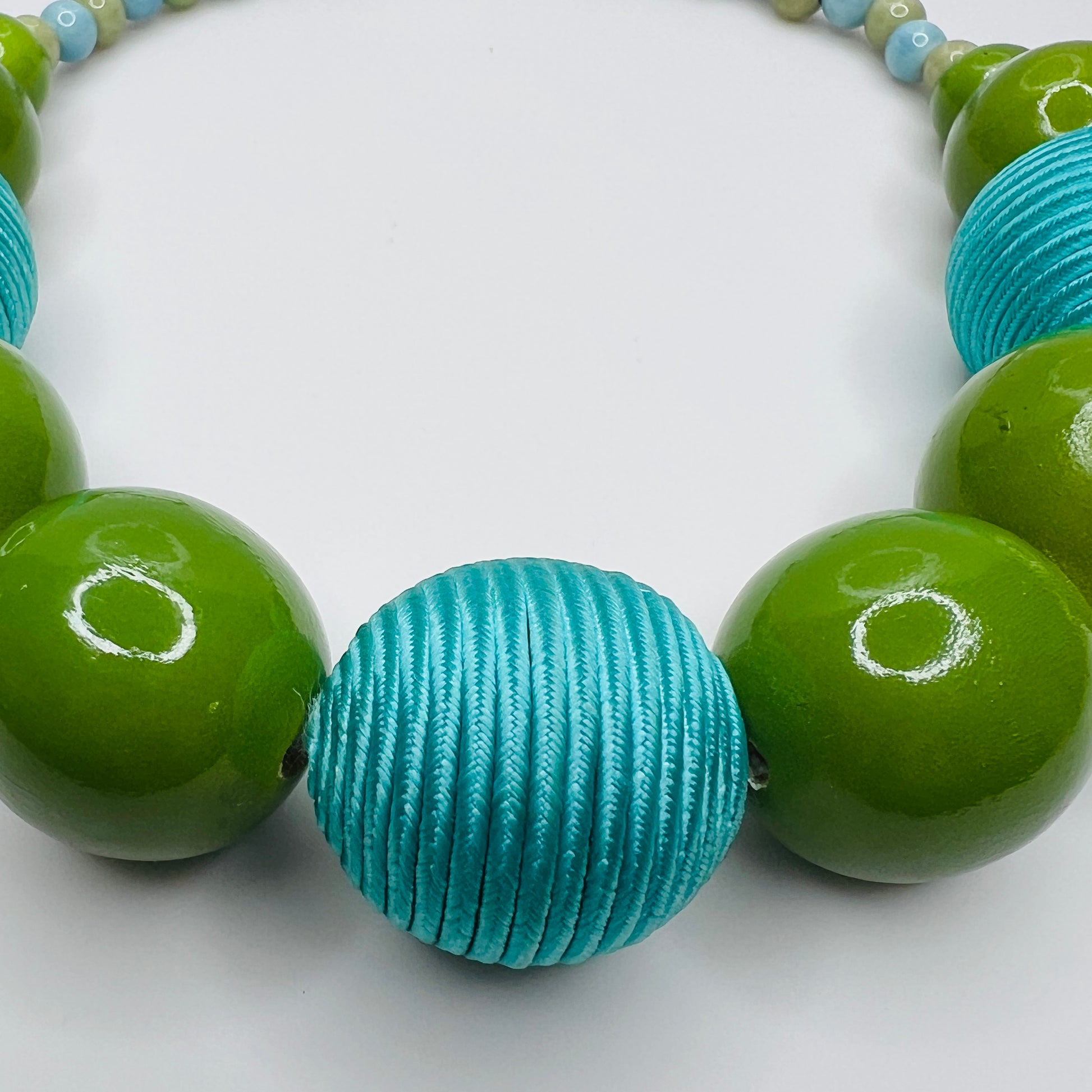 Detail of central fabric-wrapped aqua bead and glossy wood beads