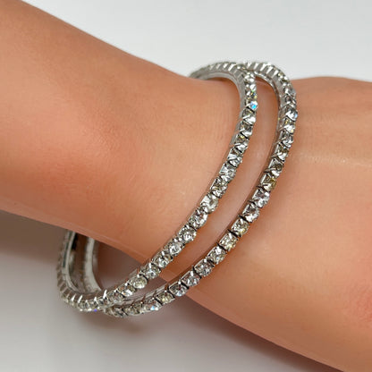 Set of two silver-tone bangle bracelets with prong-set clear rhinestones, vintage 1980s.