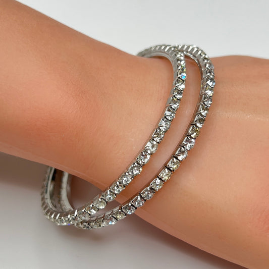Set of two silver-tone bangle bracelets with prong-set clear rhinestones, vintage 1980s.