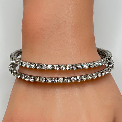 Set of two silver-tone bangle bracelets with prong-set clear rhinestones, vintage 1980s.