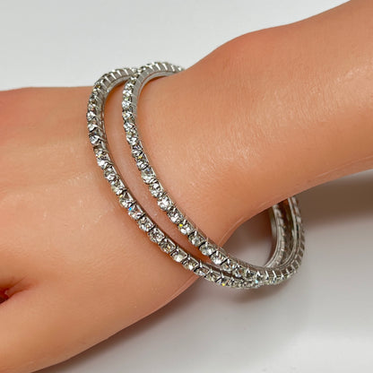 Set of two silver-tone bangle bracelets with prong-set clear rhinestones, vintage 1980s.
