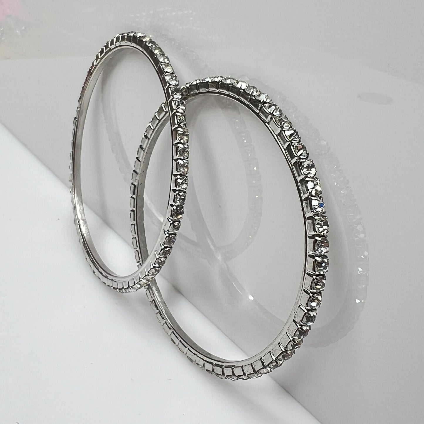 Set of two silver-tone bangle bracelets with prong-set clear rhinestones, vintage 1980s.
