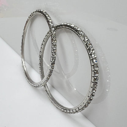 Set of two silver-tone bangle bracelets with prong-set clear rhinestones, vintage 1980s.