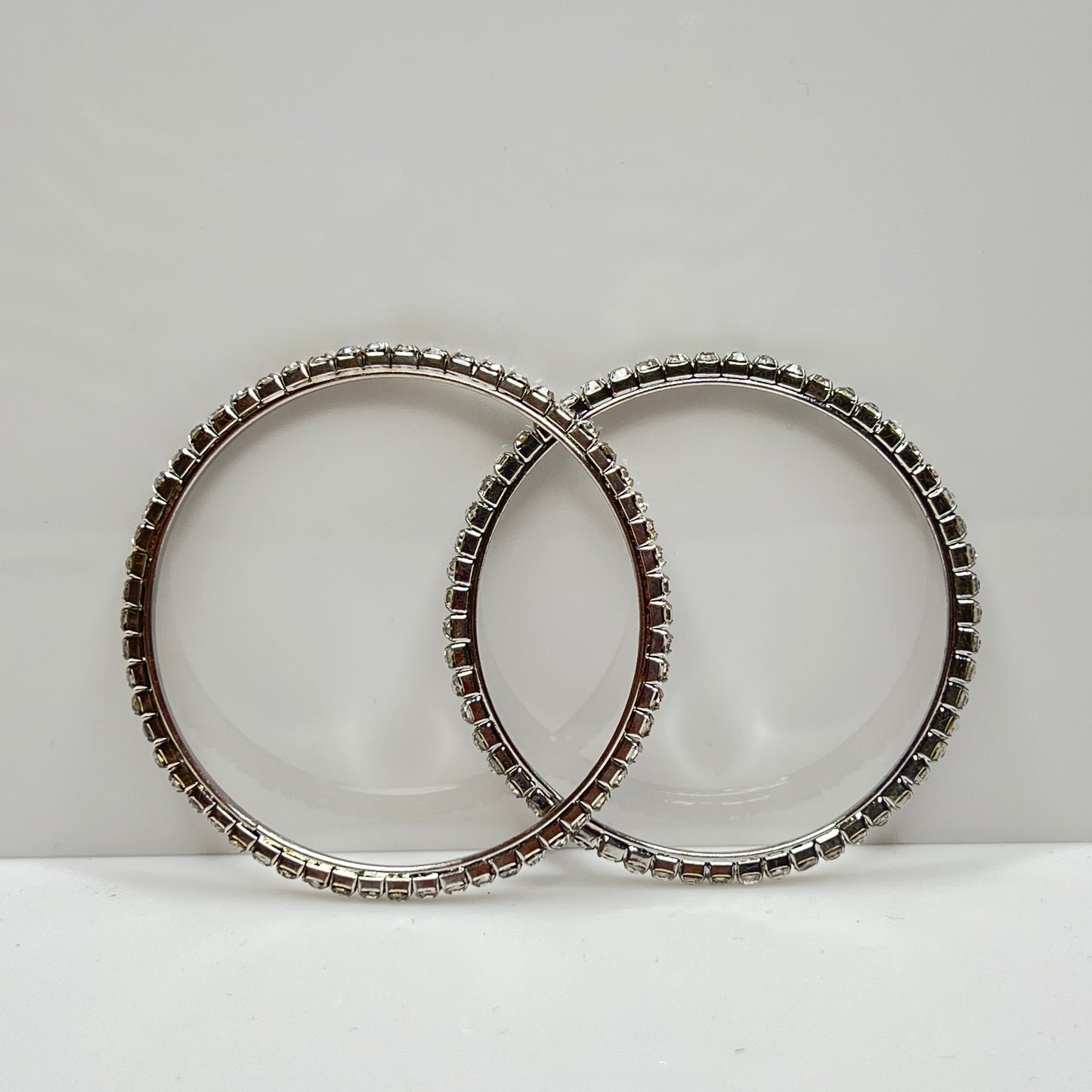 Set of two silver-tone bangle bracelets with prong-set clear rhinestones, vintage 1980s.