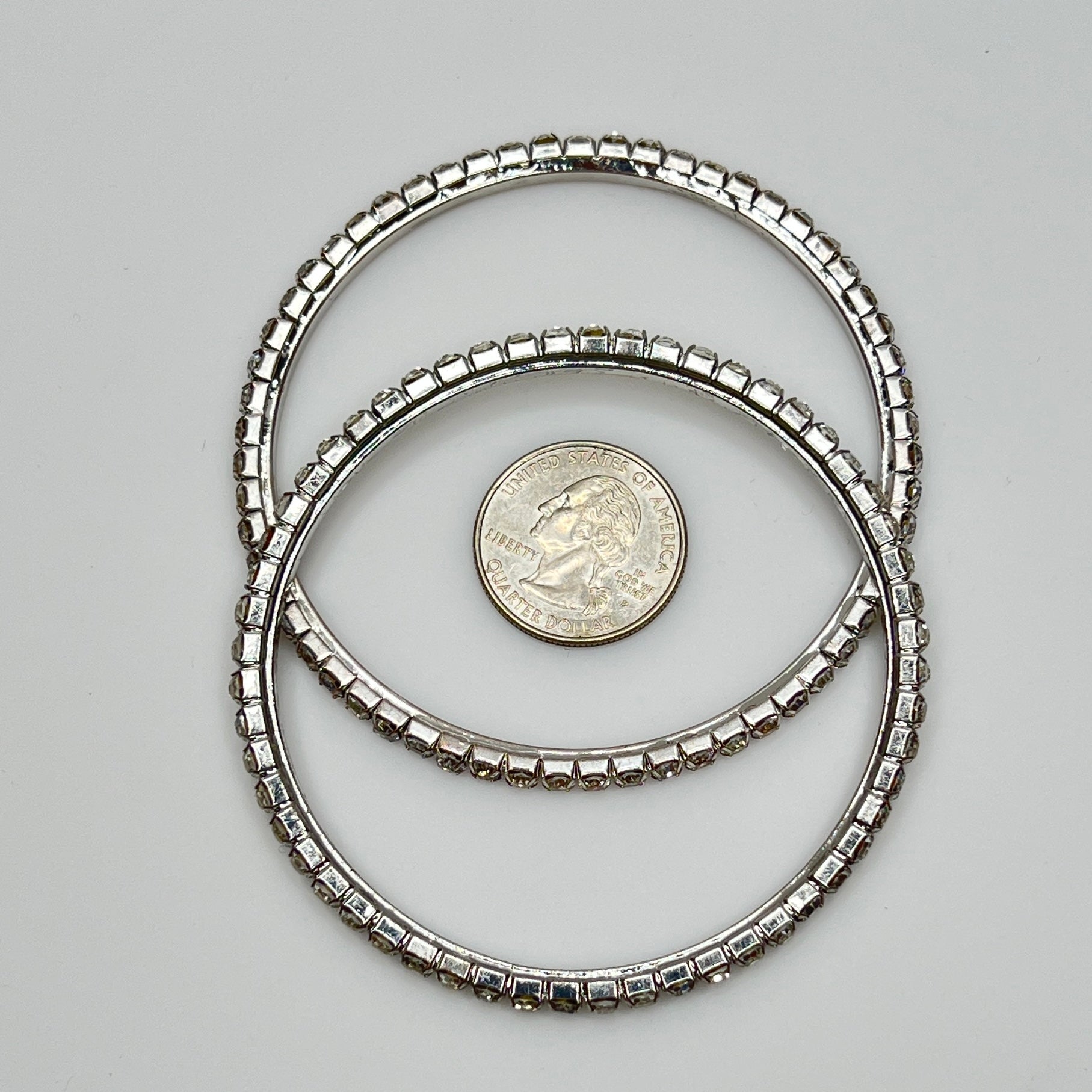 Set of two silver-tone bangle bracelets with prong-set clear rhinestones, vintage 1980s.