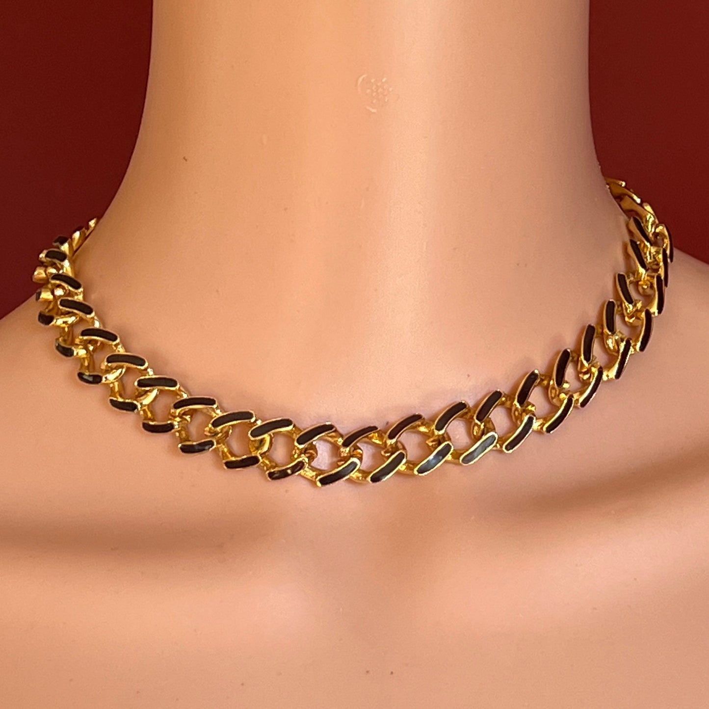 Gold chain necklace on a mannequin with a red background
