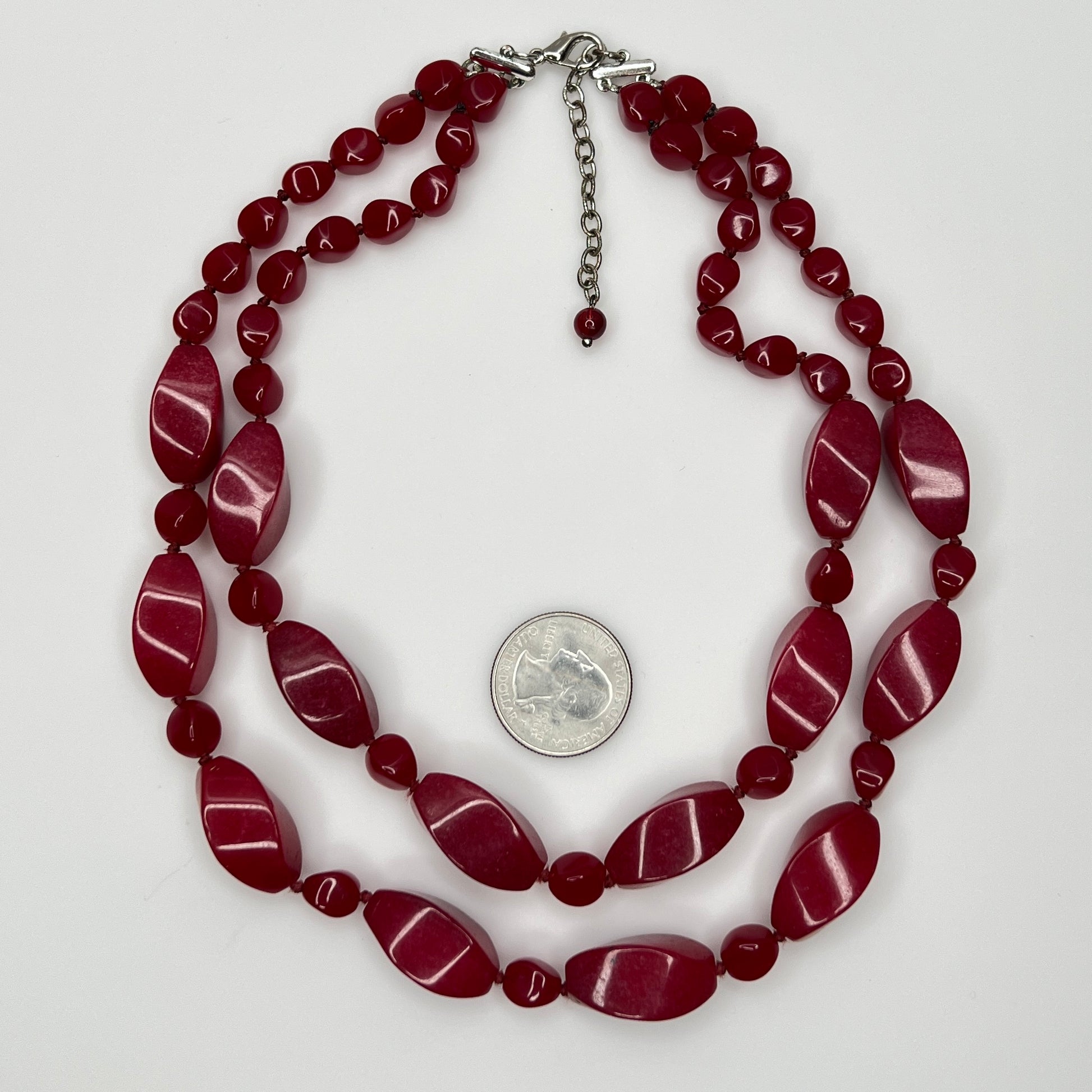 Overhead view of red glass and lucite bead necklace with lobster clasp and extender