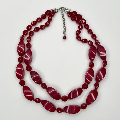 Overhead view of red glass and lucite bead necklace with lobster clasp and extender