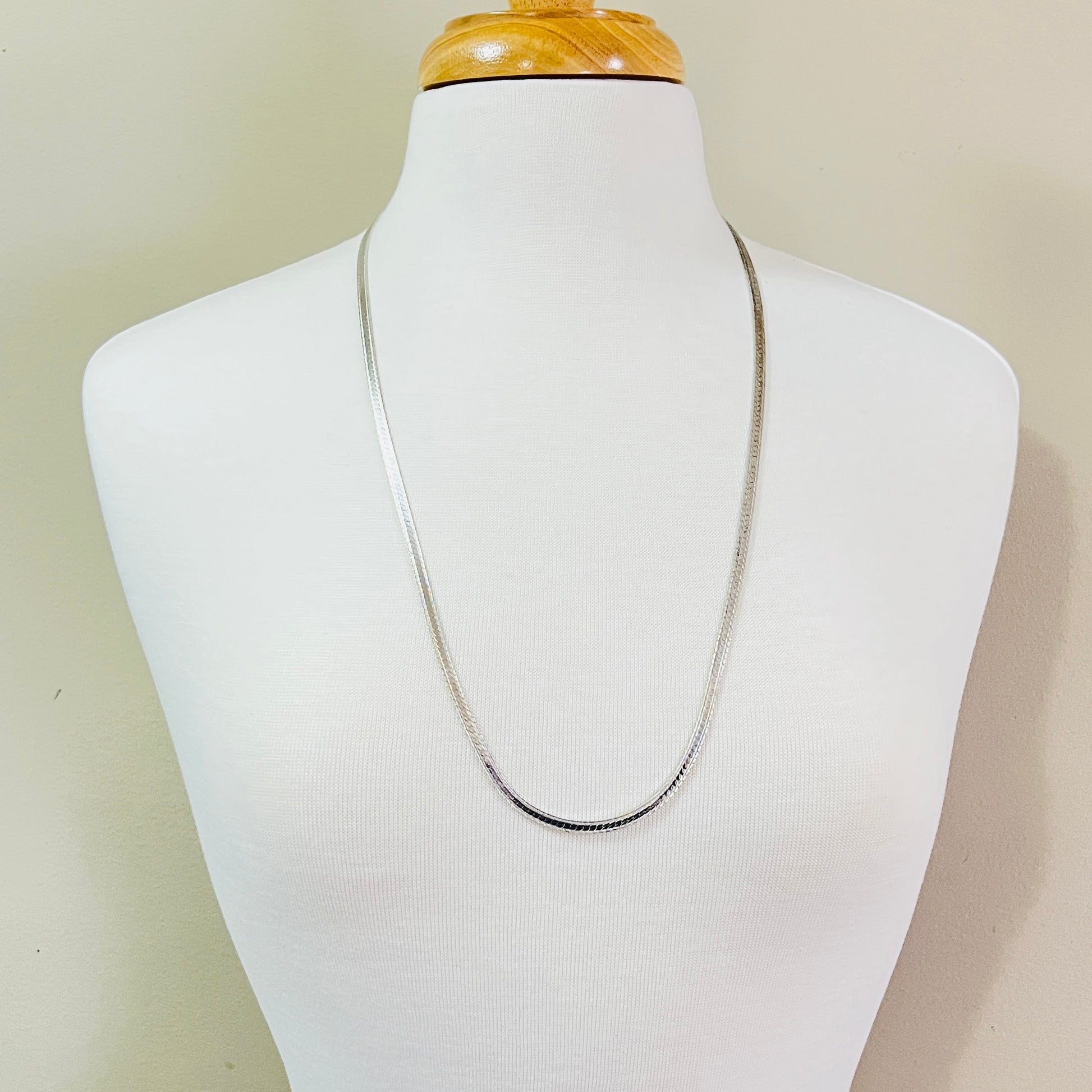Vintage sterling silver snake chain necklace displayed on jewelry bust