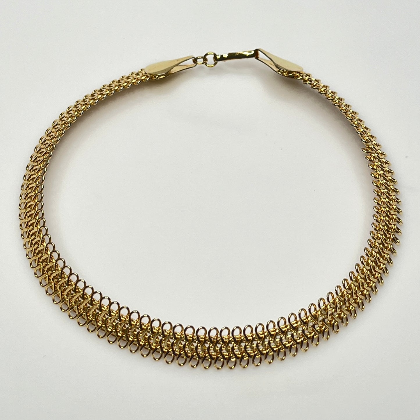Close-up of looped gold wire choker with hook clasp