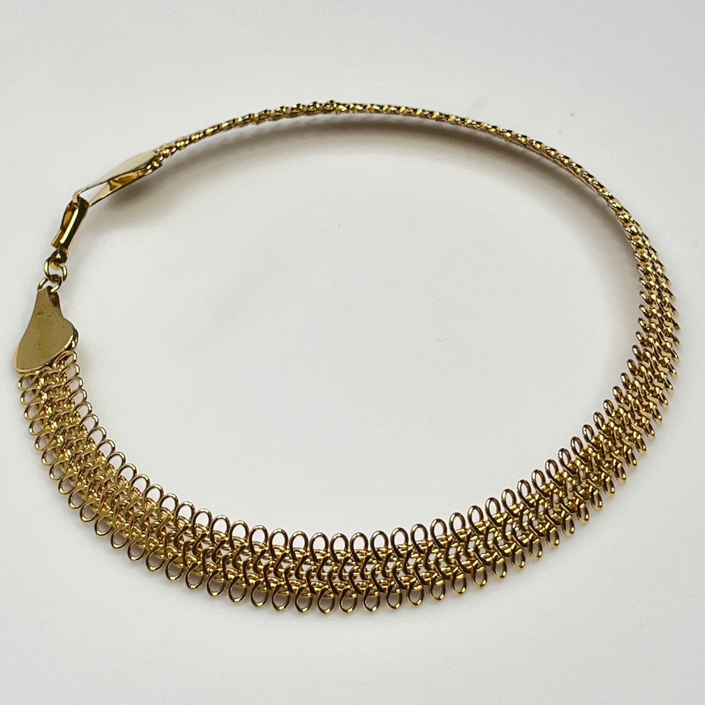 Close-up of looped gold wire choker with hook clasp