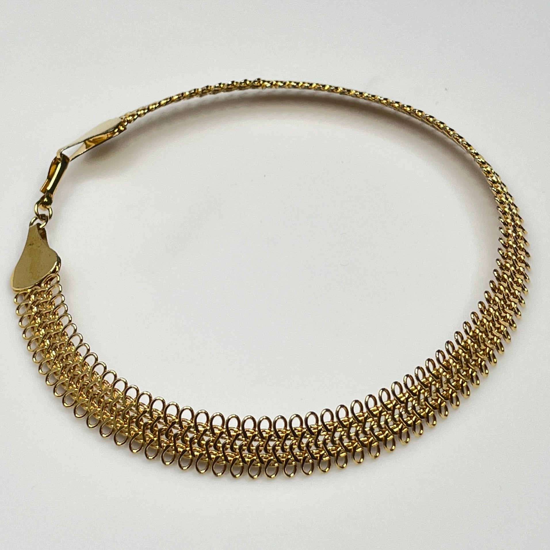 Close-up of looped gold wire choker with hook clasp