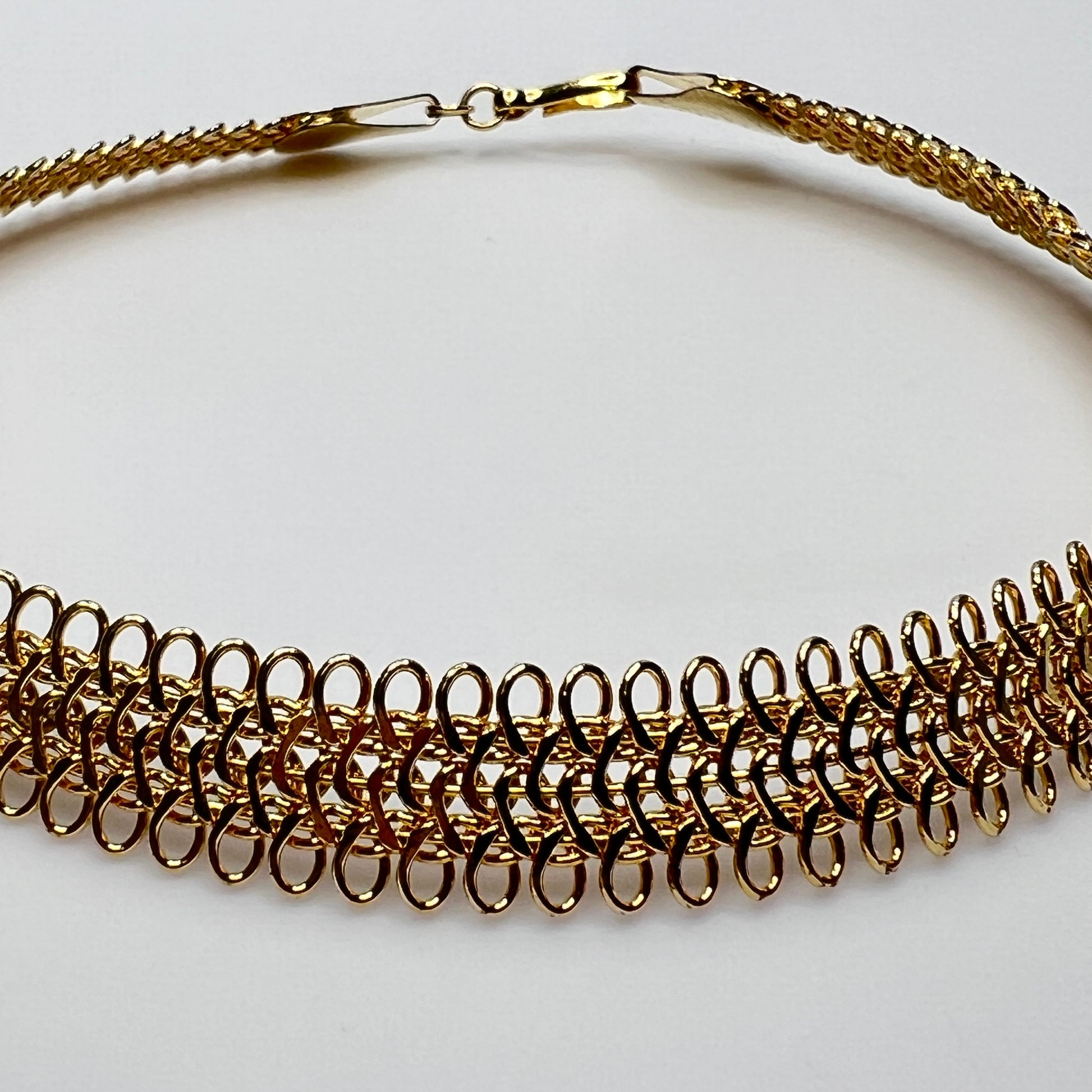 Close-up of looped gold wire choker with hook clasp