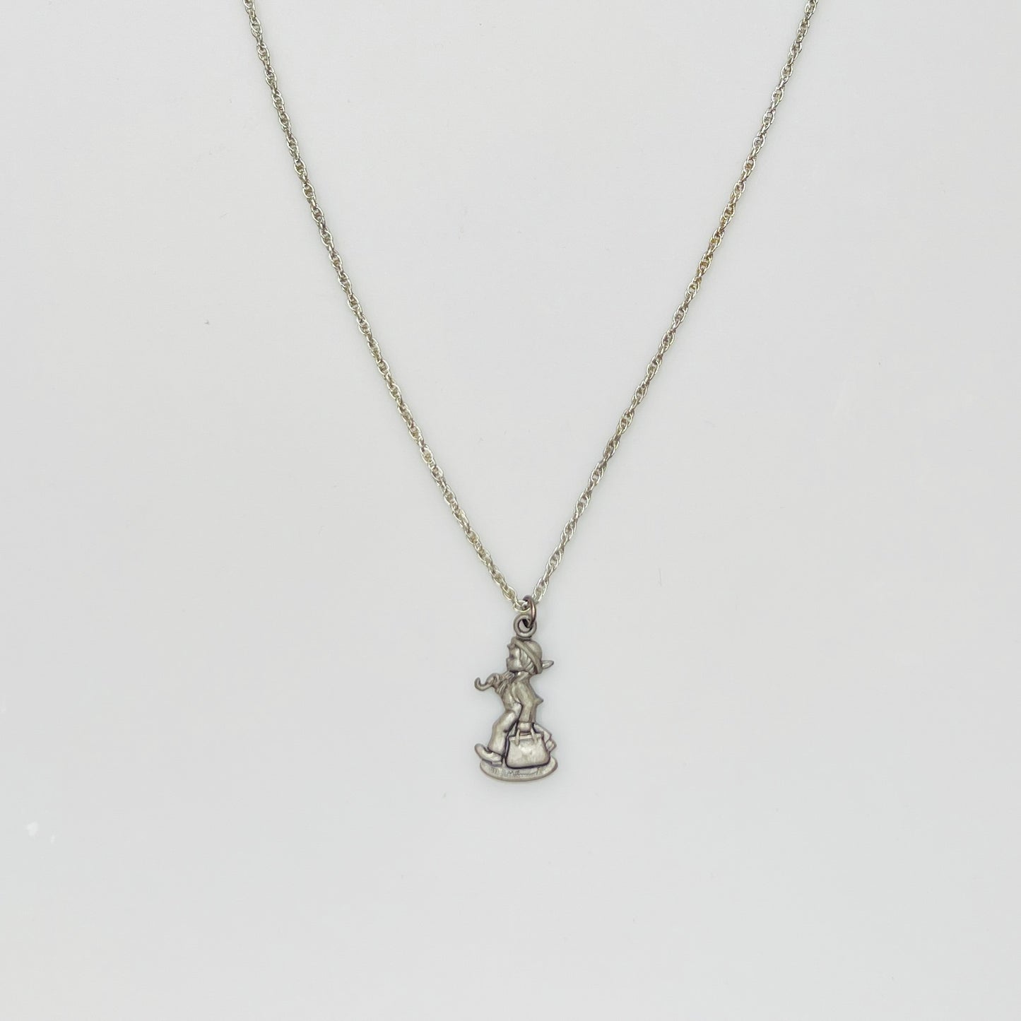 Flat lay of silver Hummel pendant necklace with twist chain