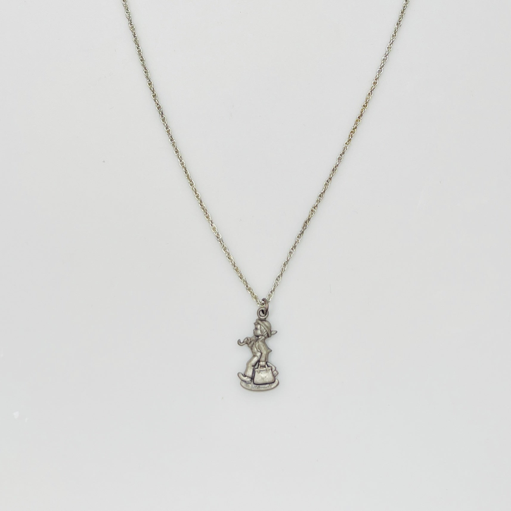Flat lay of silver Hummel pendant necklace with twist chain