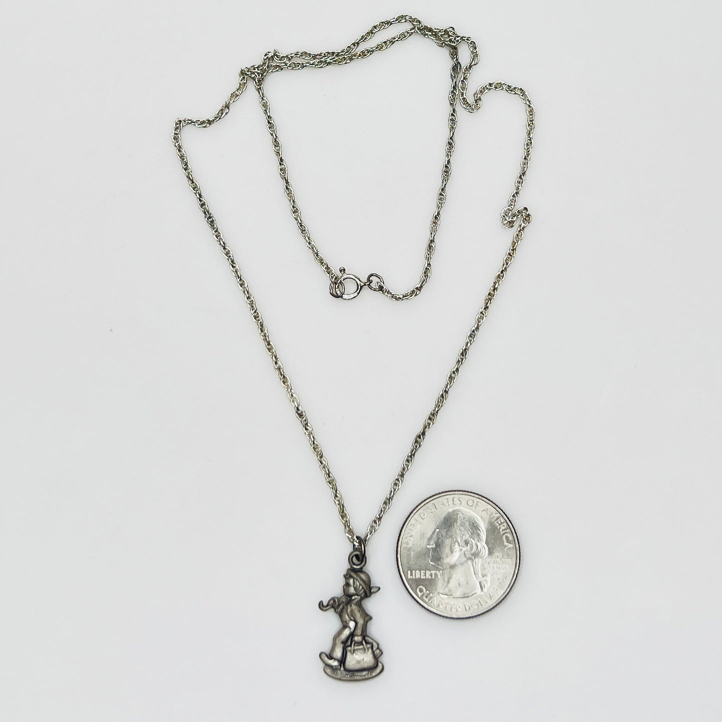 Flat lay of silver Hummel pendant necklace with twist chain