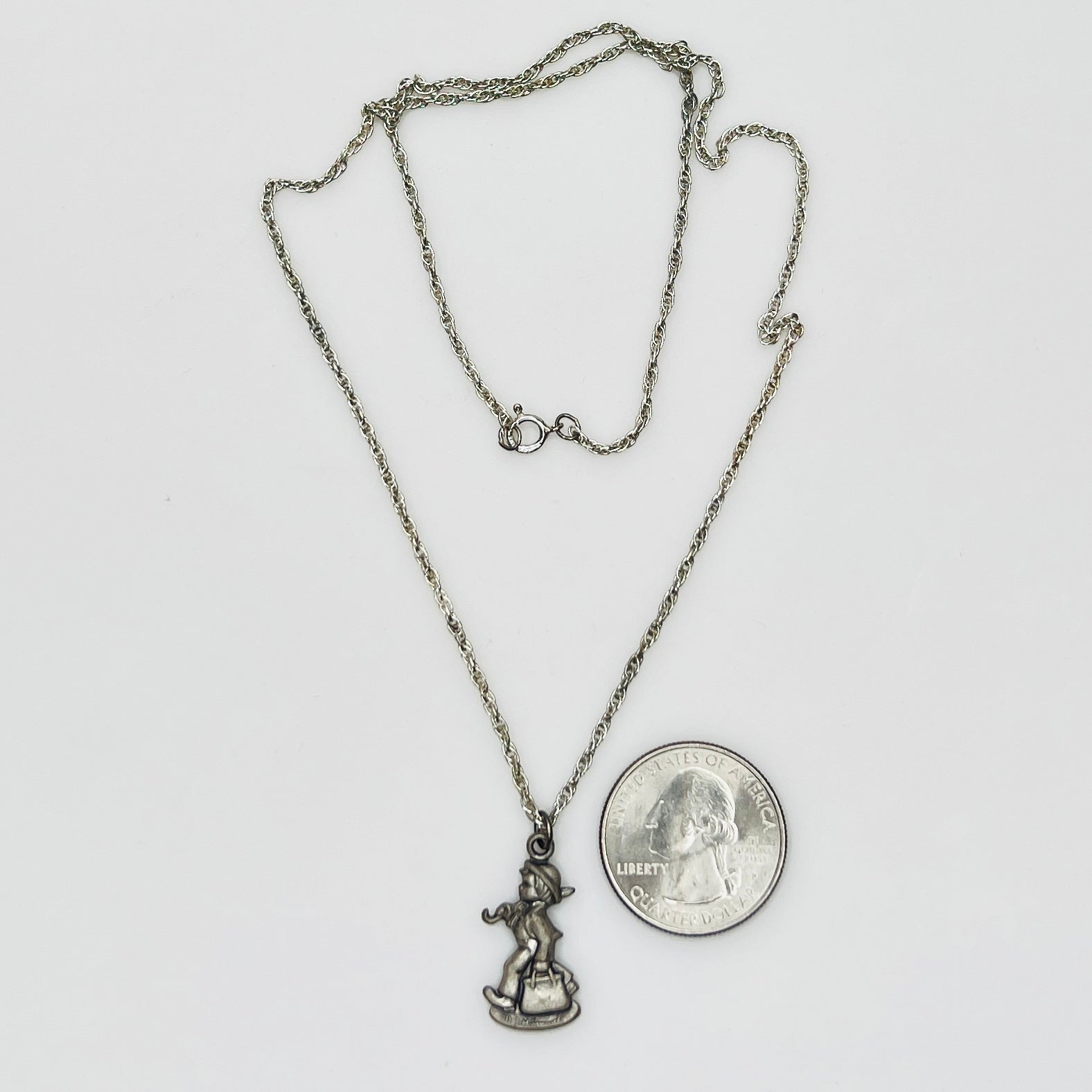 Flat lay of silver Hummel pendant necklace with twist chain