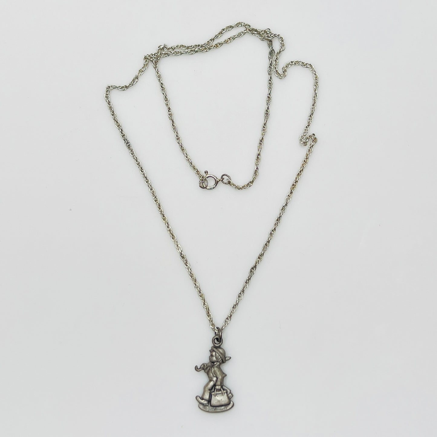 Flat lay of silver Hummel pendant necklace with twist chain