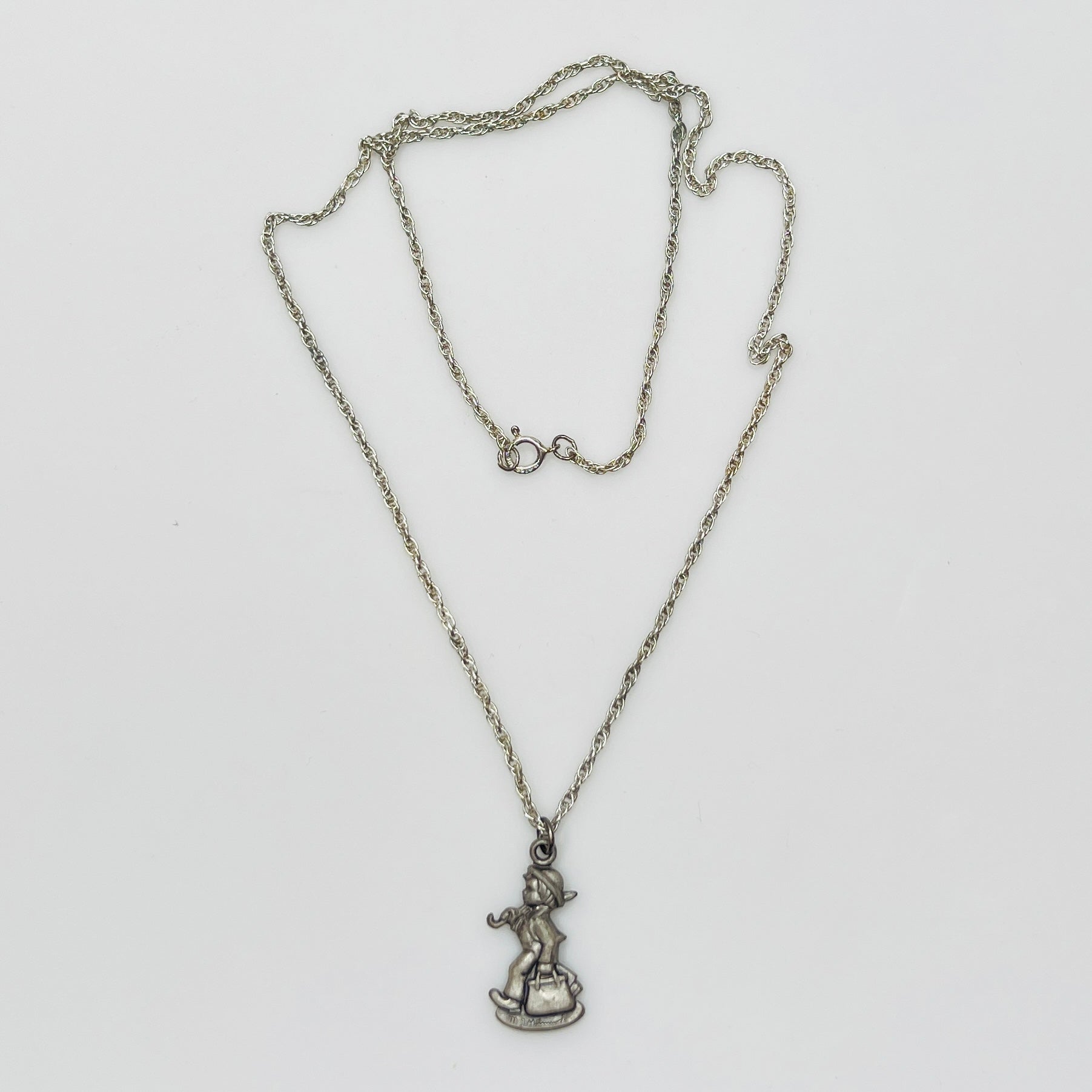 Flat lay of silver Hummel pendant necklace with twist chain