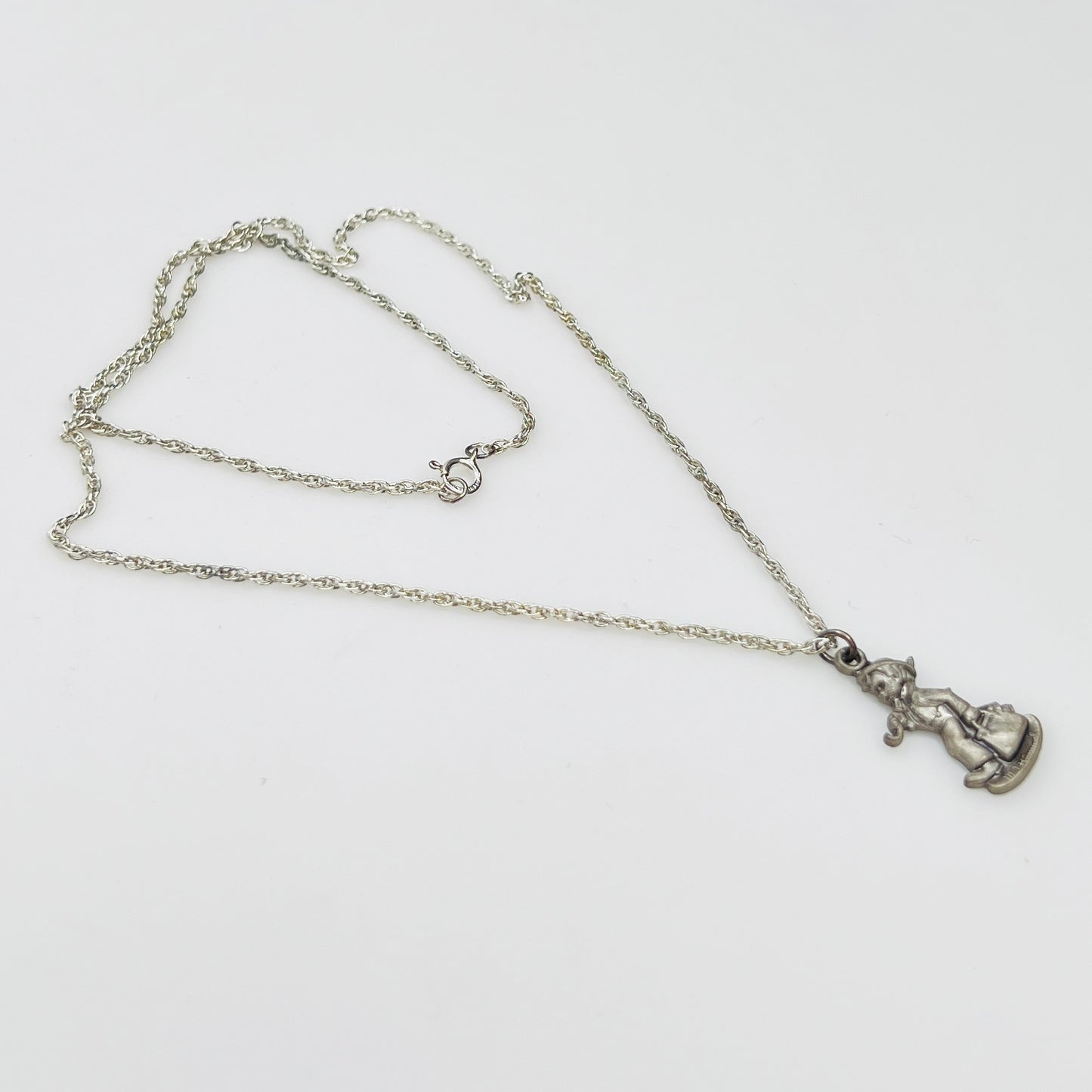 Side view Flat lay of silver Hummel pendant necklace with twist chain