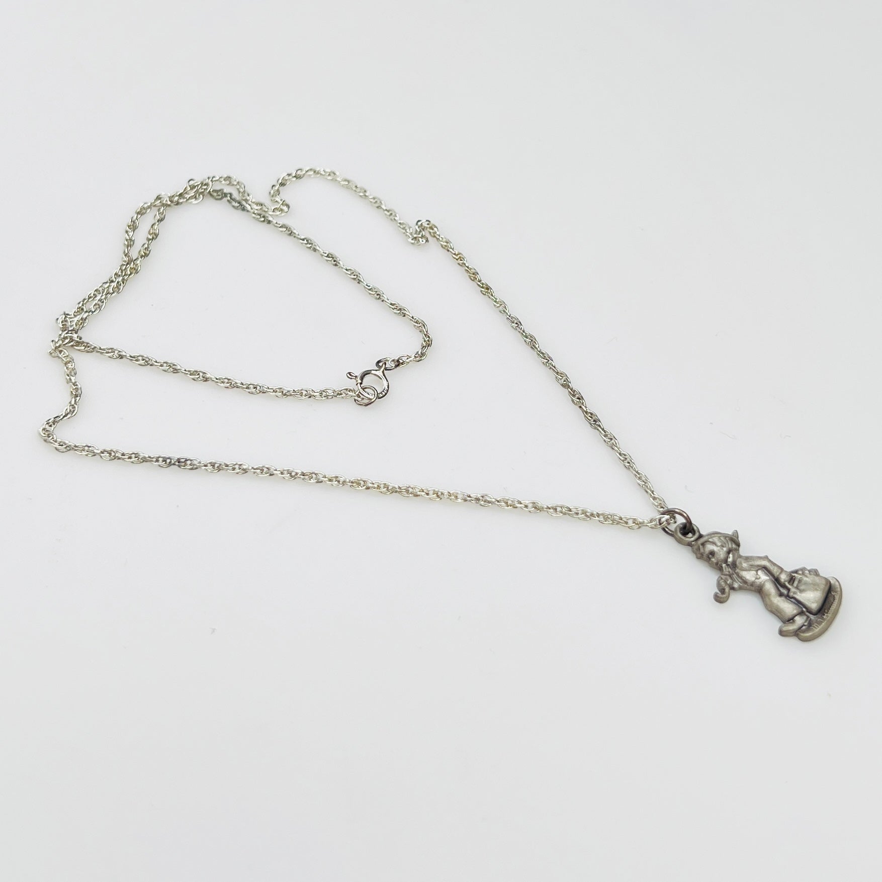Side view Flat lay of silver Hummel pendant necklace with twist chain