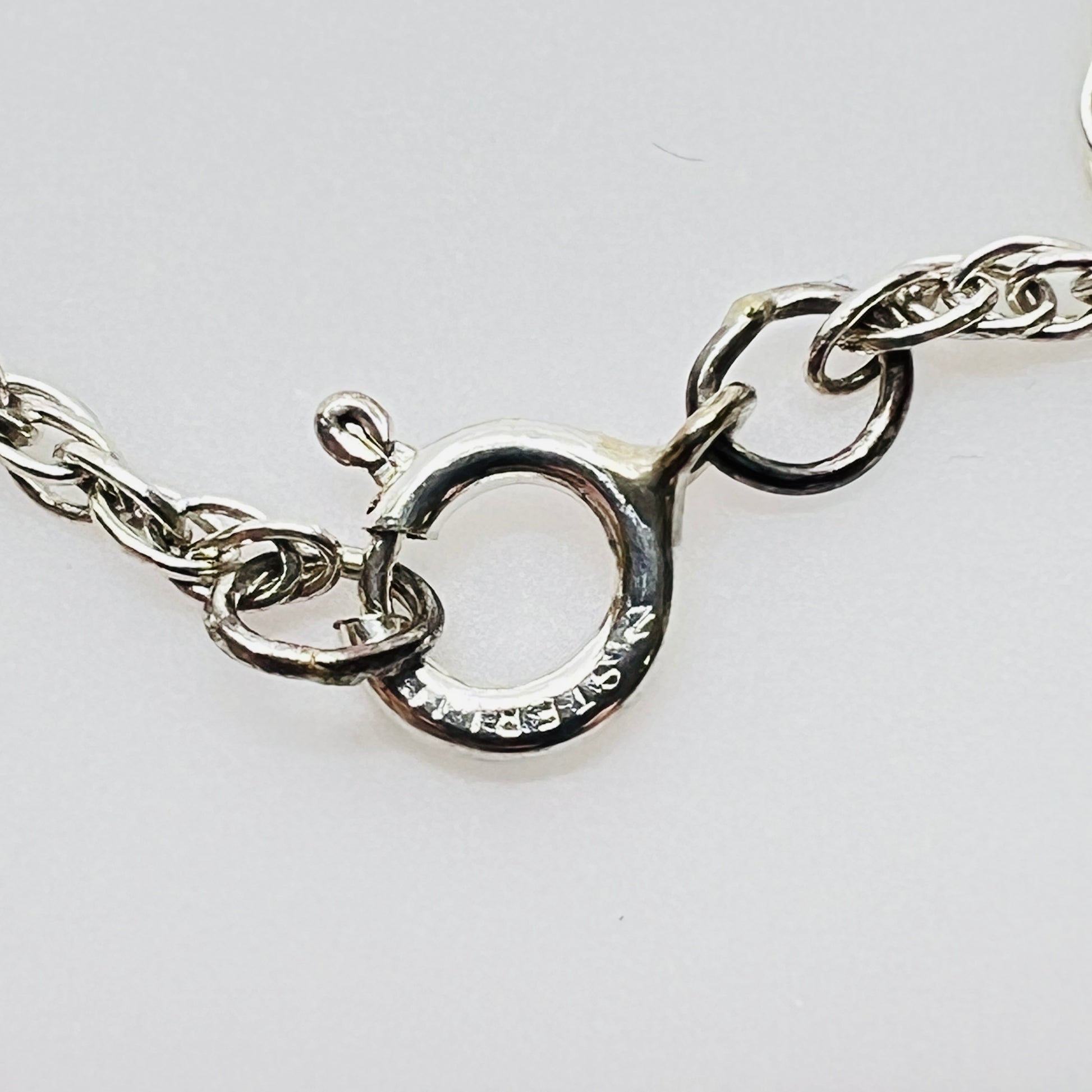 Clasp view Flat lay of silver Hummel pendant necklace with twist chain showing sterling stamp