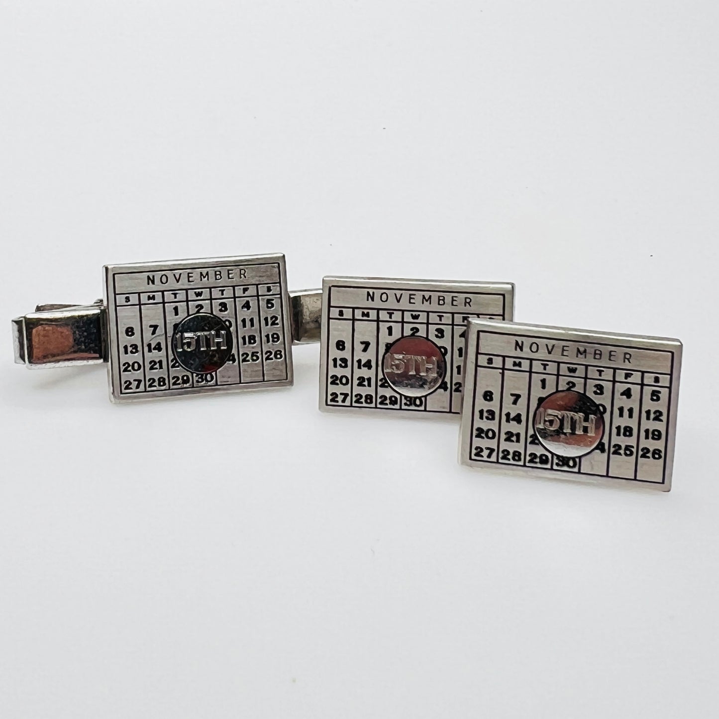 Close-up of cufflinks and tie bar showing November 15th detail