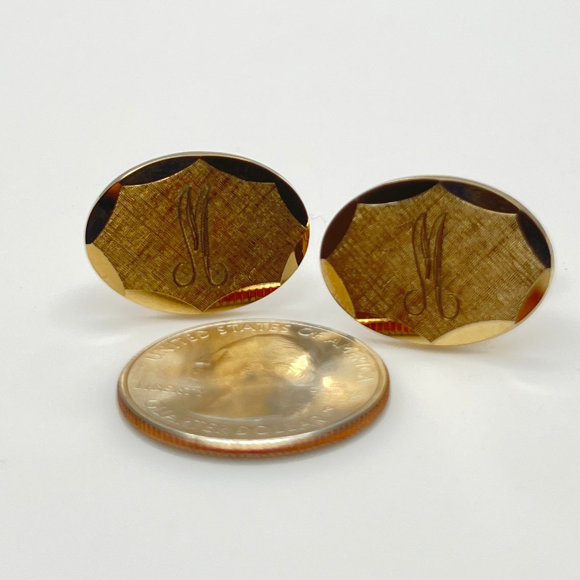Close-up of monogrammed “M” cufflinks and matching gold-tone tie tack