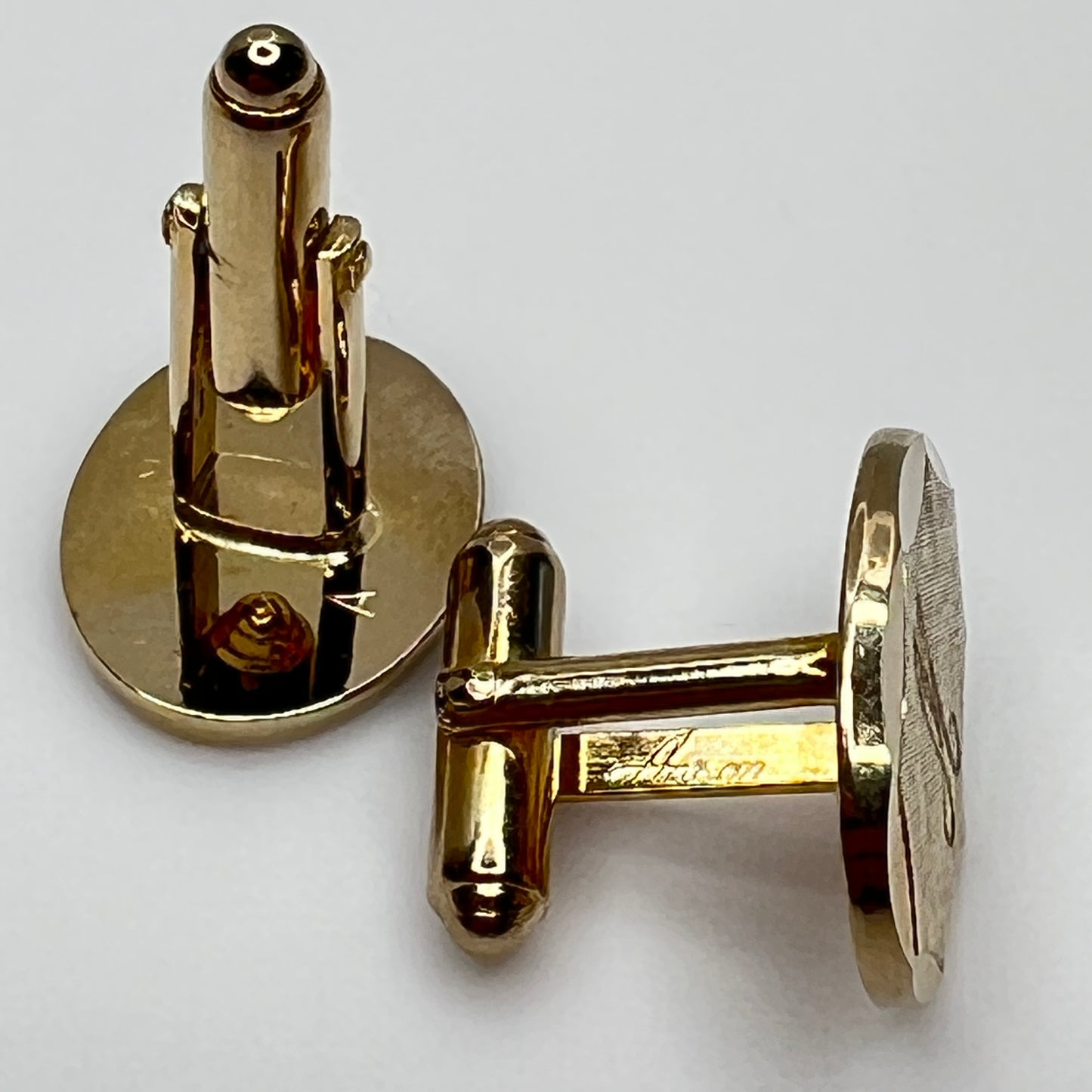 Close-up of monogrammed “M” cufflinks and matching gold-tone tie tack