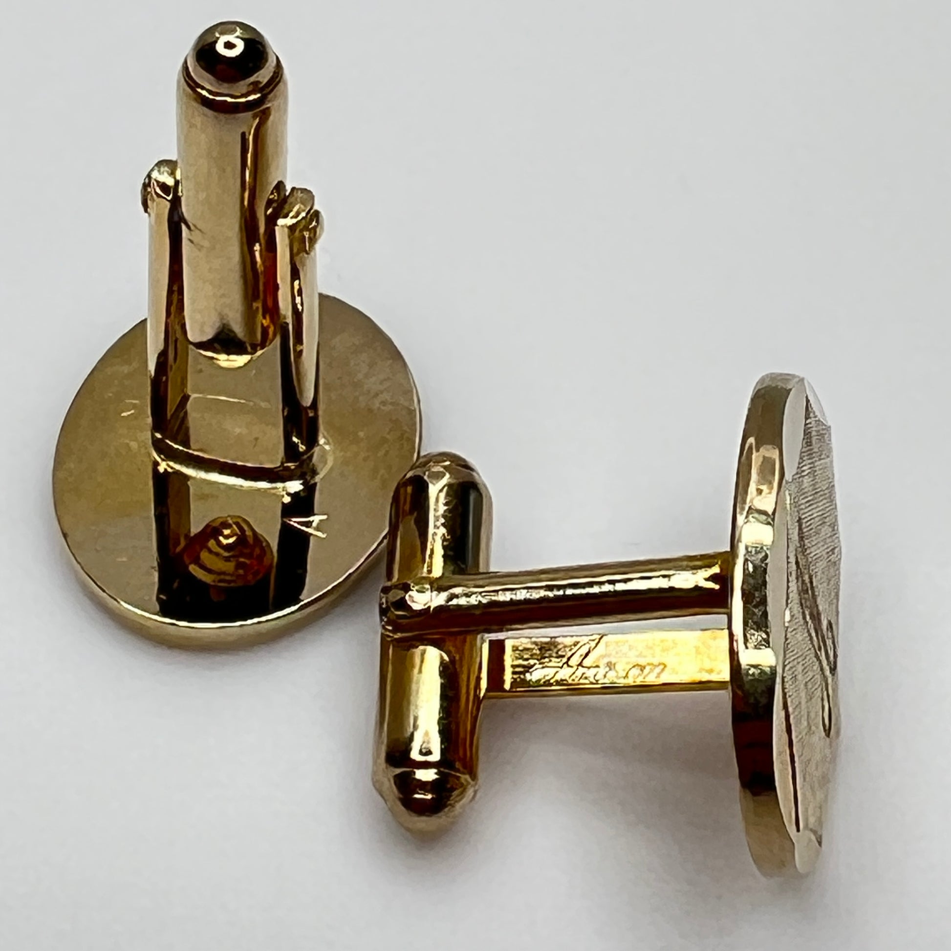 Close-up of monogrammed “M” cufflinks and matching gold-tone tie tack