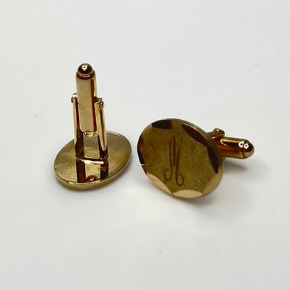 Close-up of monogrammed “M” cufflinks and matching gold-tone tie tack