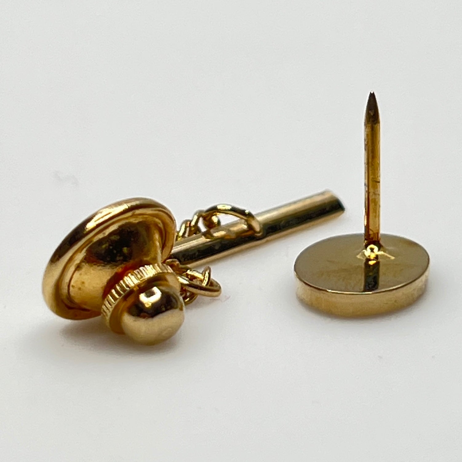 Close-up of monogrammed “M” cufflinks and matching gold-tone tie tack