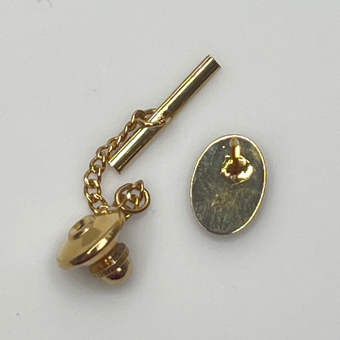 Close-up of monogrammed “M” cufflinks and matching gold-tone tie tack