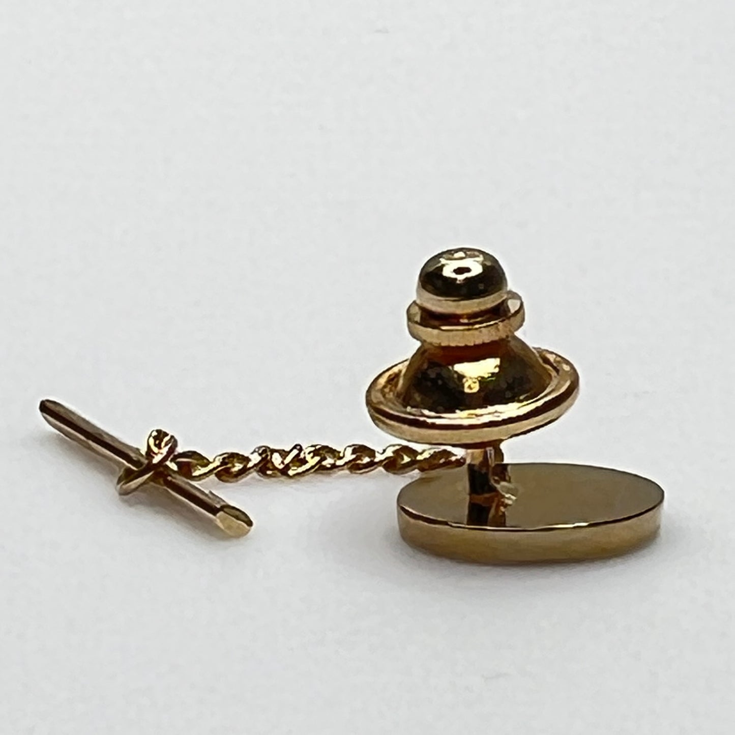 Close-up of monogrammed “M” cufflinks and matching gold-tone tie tack