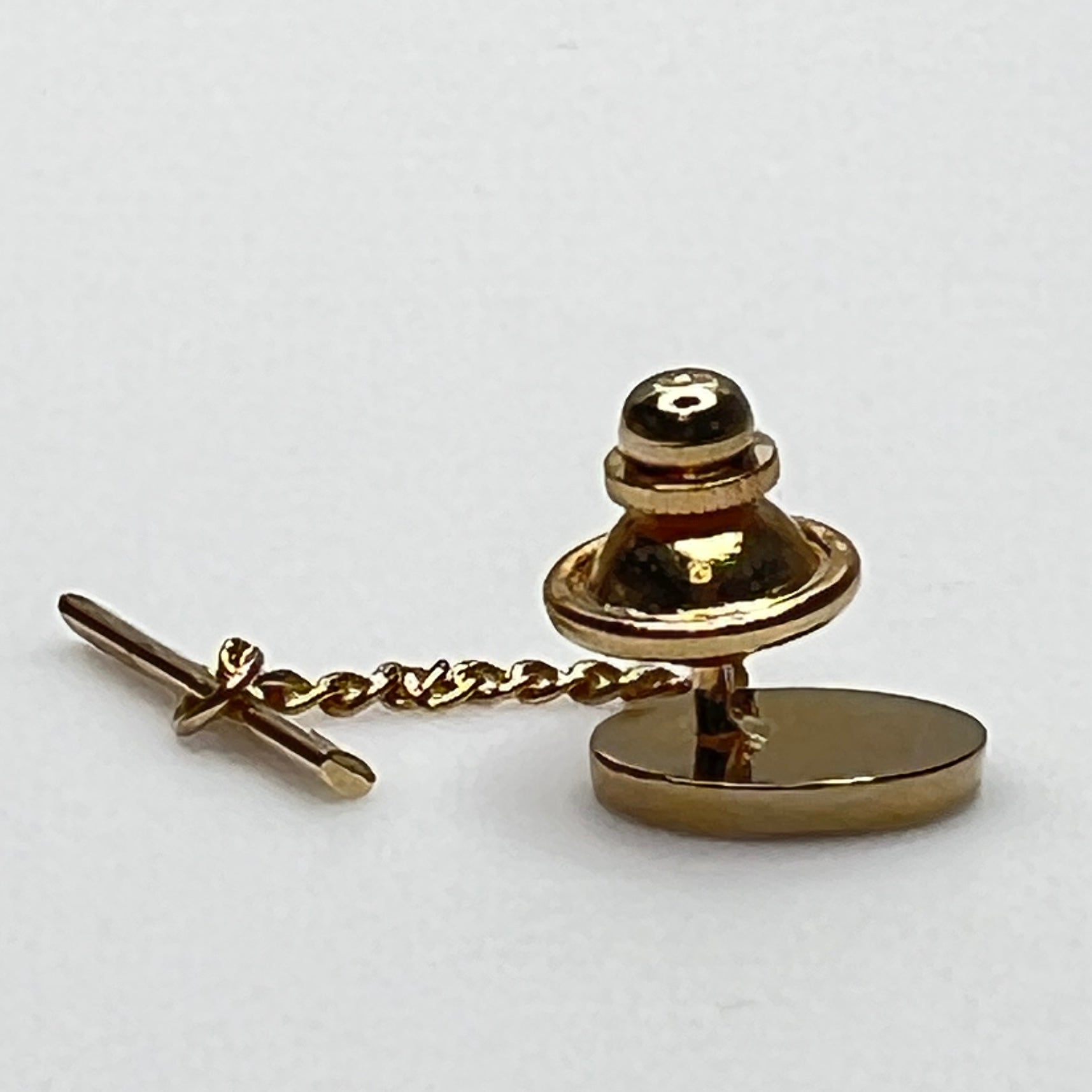 Close-up of monogrammed “M” cufflinks and matching gold-tone tie tack
