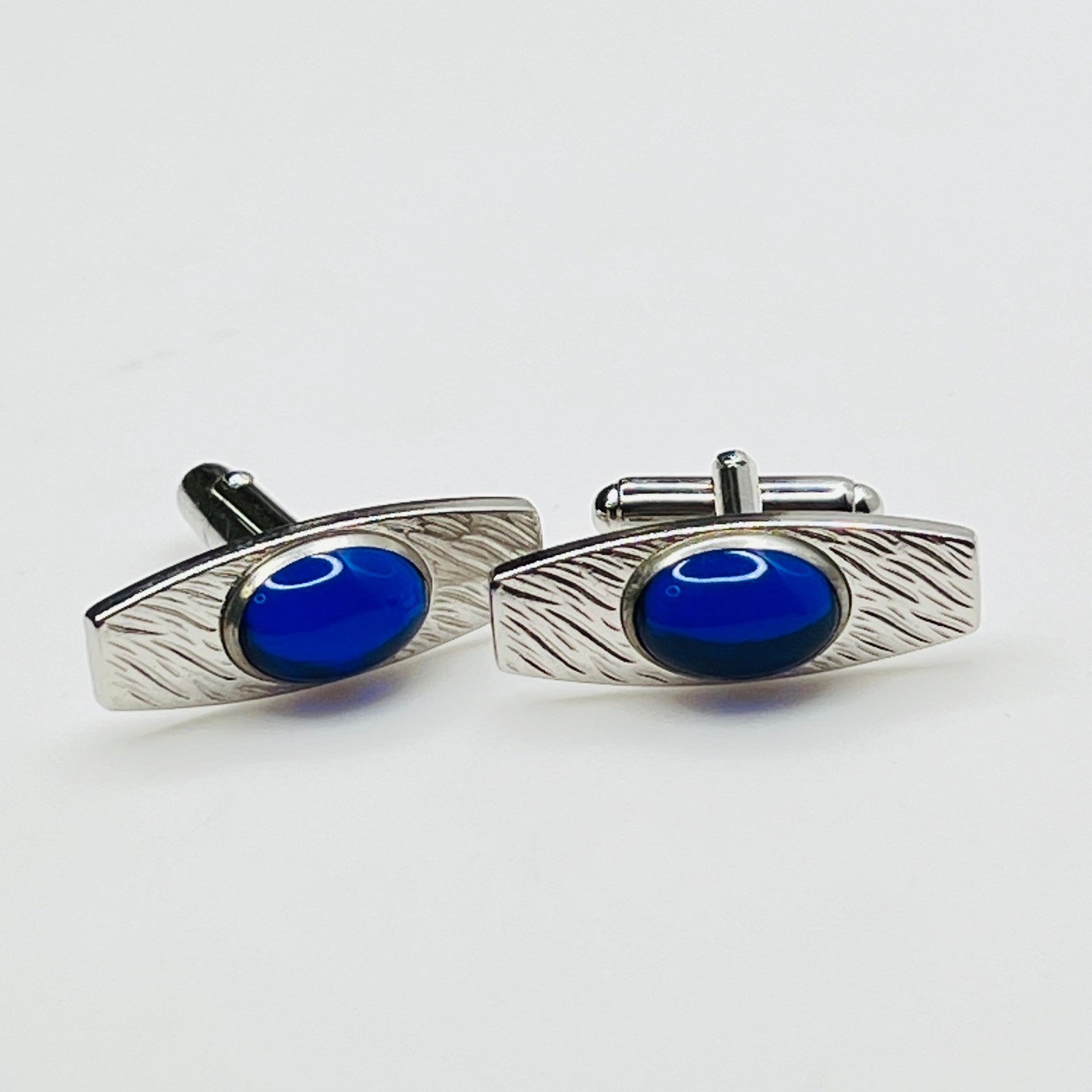 Silver-tone cufflinks with textured finish and vivid blue lucite cabochons, signed Anson