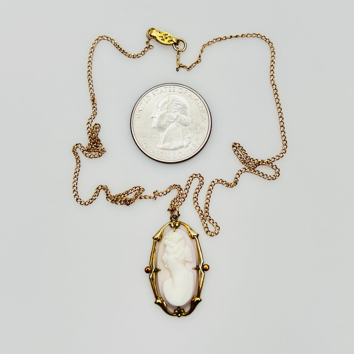 Vintage cameo necklace next to coin for size reference