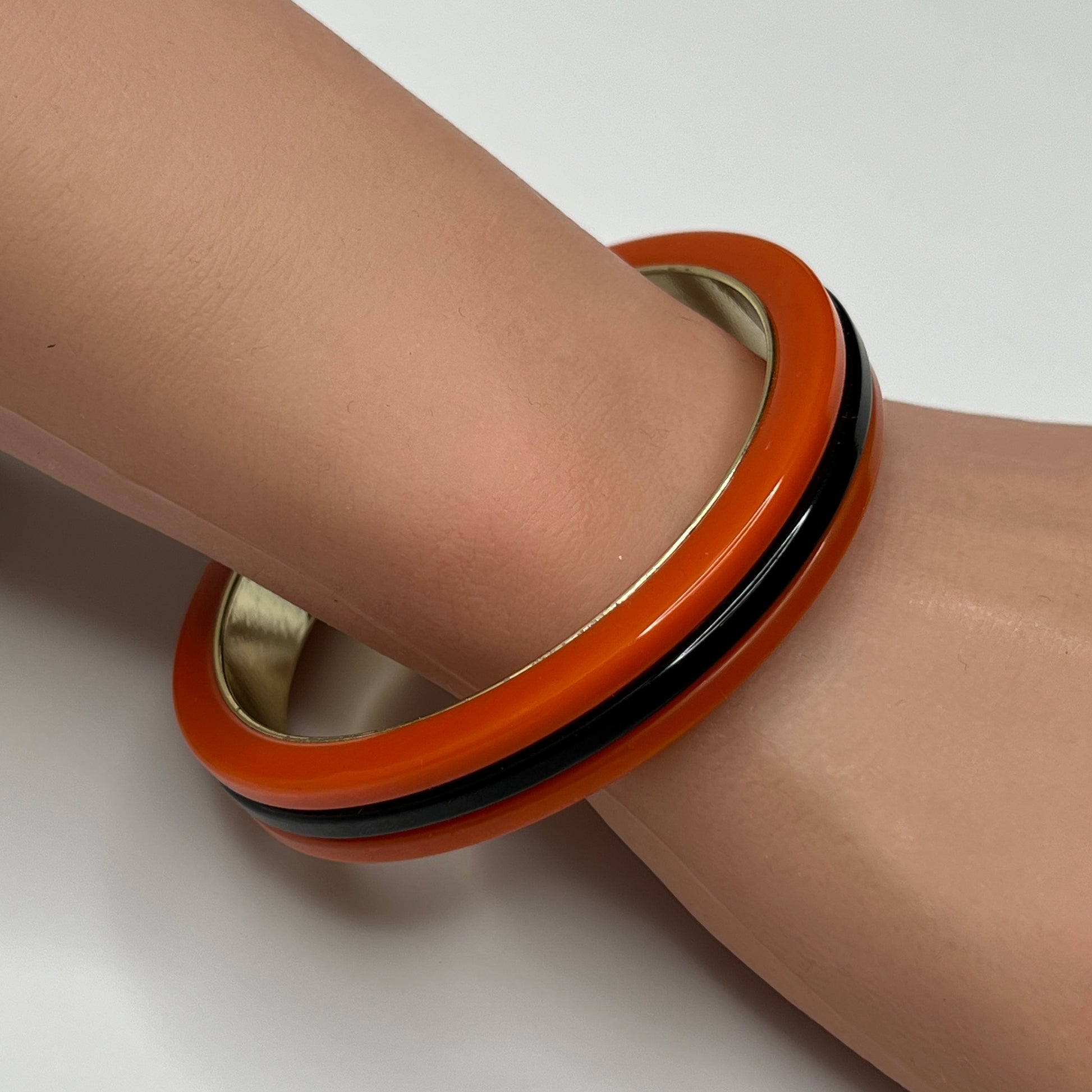 Orange Bakelite bangle bracelet with black stripe and gold-tone interior