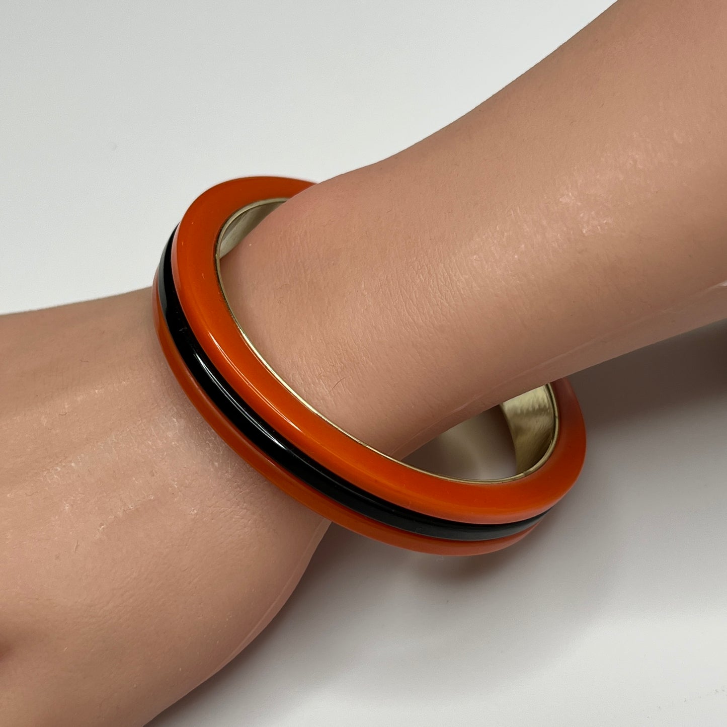 Orange Bakelite bangle bracelet with black stripe and gold-tone interior