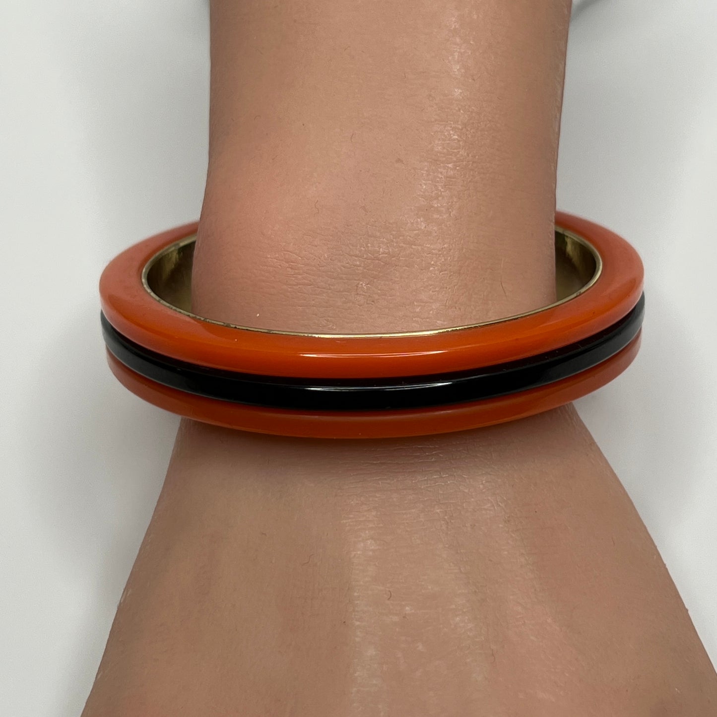 Orange Bakelite bangle bracelet with black stripe and gold-tone interior