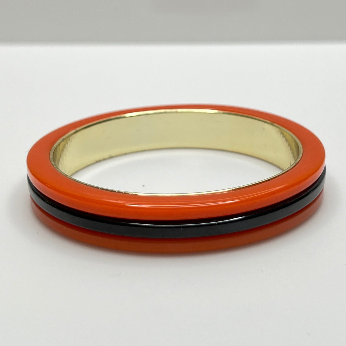 Orange Bakelite bangle bracelet with black stripe and gold-tone interior