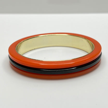 Orange Bakelite bangle bracelet with black stripe and gold-tone interior