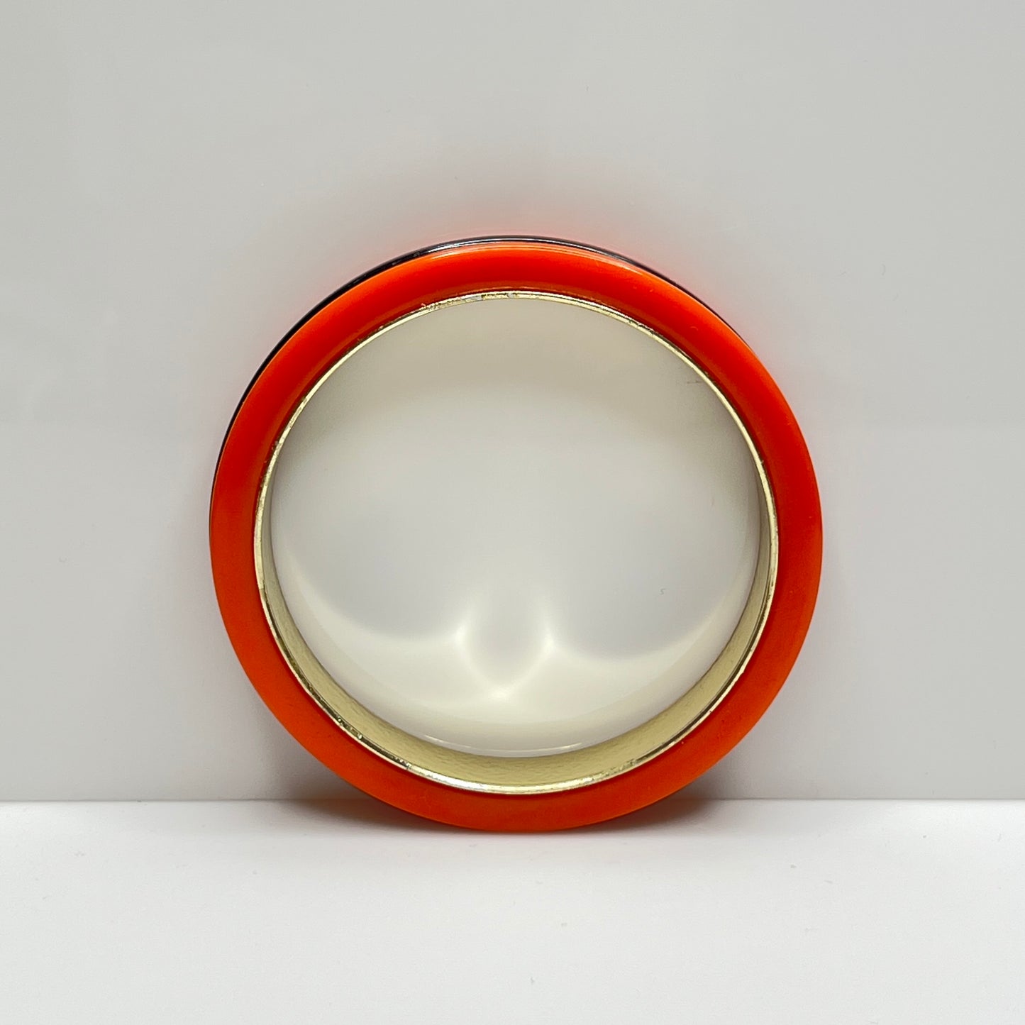 Orange Bakelite bangle bracelet with black stripe and gold-tone interior