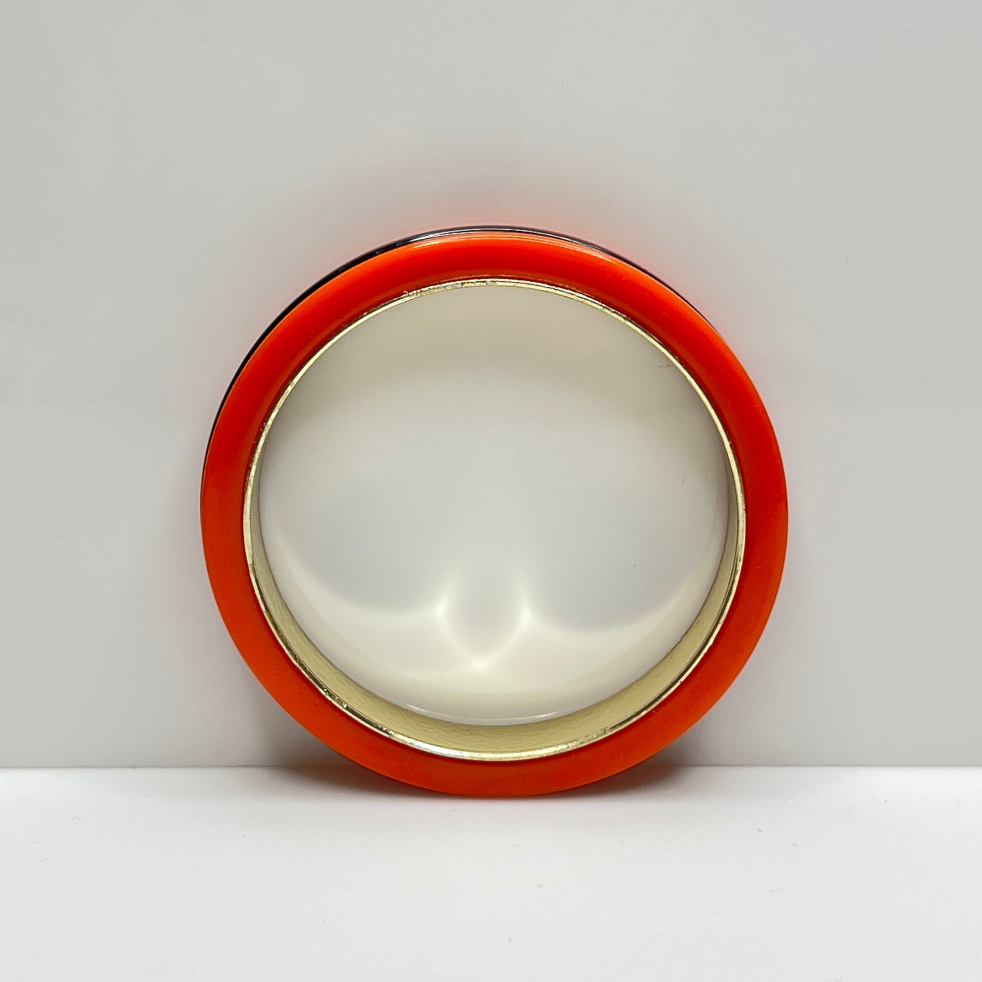 Orange Bakelite bangle bracelet with black stripe and gold-tone interior