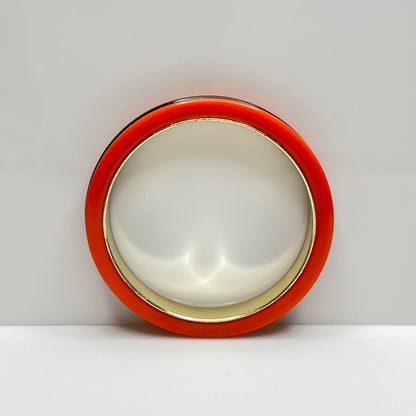 Orange Bakelite bangle bracelet with black stripe and gold-tone interior