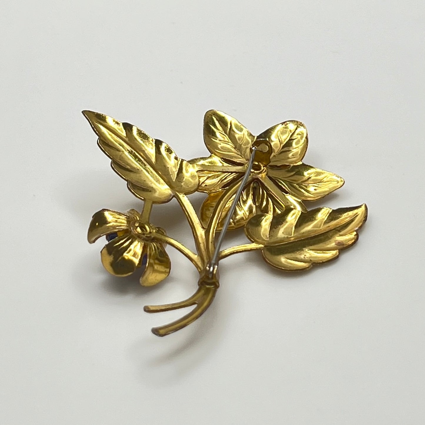 Vintage brass flower brooch with two sapphire-blue rhinestones and leaf details, 1940s style.