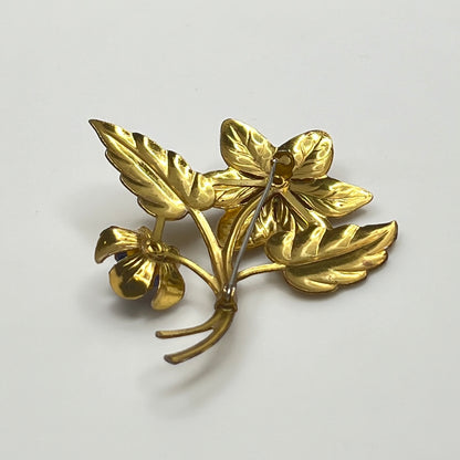 Vintage brass flower brooch with two sapphire-blue rhinestones and leaf details, 1940s style.