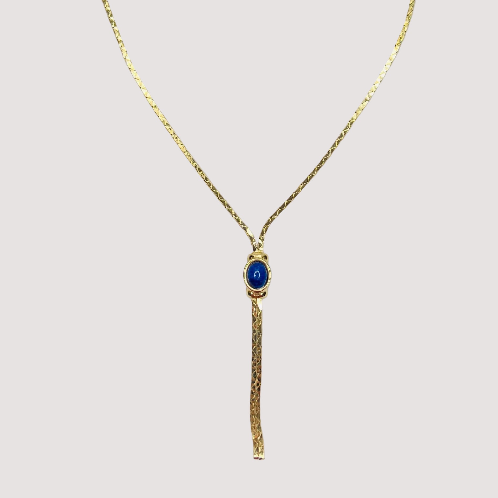 Full view of necklace with lariat drop and blue stone on white background