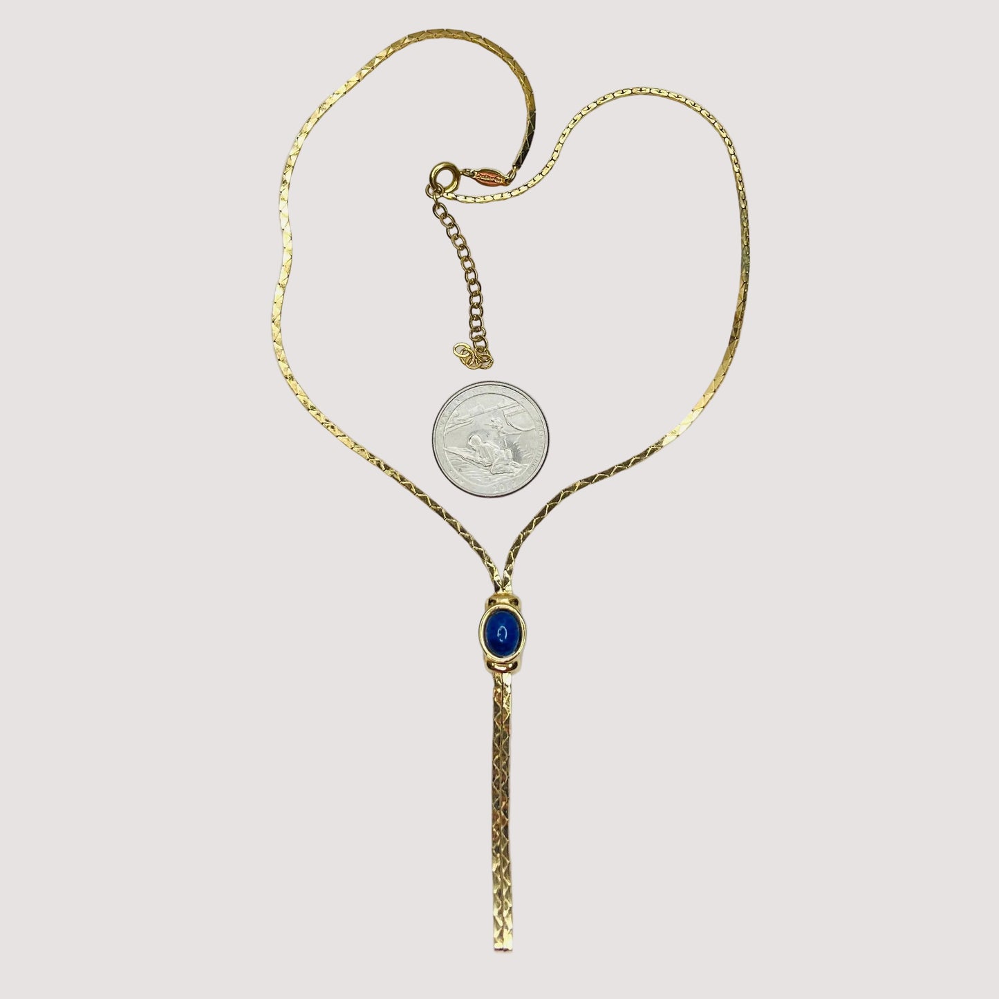 Full view of necklace with lariat drop and blue stone on white background